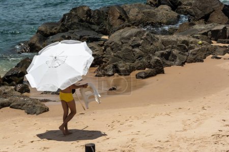 Téléchargez les photos : Salvador, Bahia, Brésil - 14 janvier 2022 : Des gens sur la plage mettent des parasols sur le sable. Plage de Porto da Barra, Salvador, Bahia. - en image libre de droit