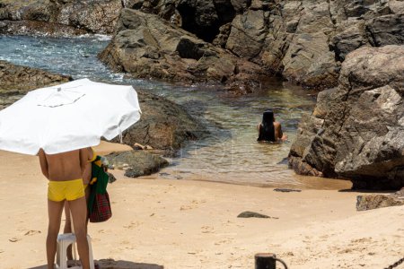 Téléchargez les photos : Salvador, Bahia, Brésil - 14 janvier 2022 : Des gens sur la plage mettent des parasols sur le sable. Plage de Porto da Barra, Salvador, Bahia. - en image libre de droit