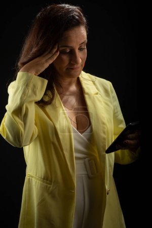 Téléchargez les photos : Coaching femme, tenue jaune, regarder les nouvelles sur le téléphone portable. Gestion communicative et motivationnelle. Isolé sur fond noir. - en image libre de droit
