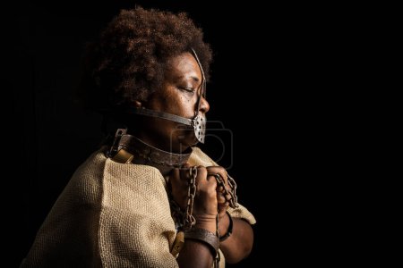 Photo for Portrait of a black woman with chains on her hands and an iron mask on her face representing the slave Anastacia. Slavery in Brazil. - Royalty Free Image