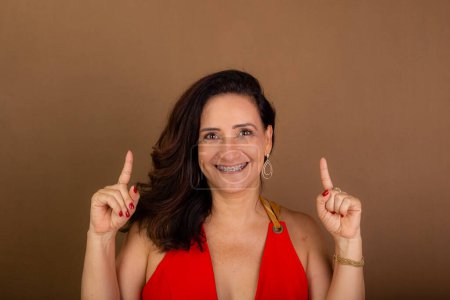 Photo for Portrait of beautiful confident and cheerful coaching woman pointing up. Democratic management. Motivating person. Isolated on brown background. - Royalty Free Image