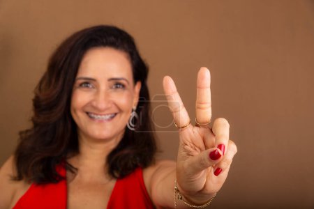 Photo for Portrait of beautiful confident cheerful woman doing number two with her fingers. Motivating person. Isolated on brown background. - Royalty Free Image