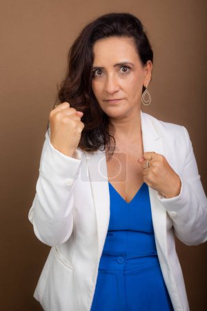 Photo for Coaching woman with clenched fists. Democratic and motivating management. Isolated on brown background. - Royalty Free Image