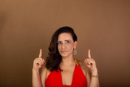 Photo for Portrait of beautiful confident and cheerful coaching woman pointing up. Democratic management. Motivating person. Isolated on brown background. - Royalty Free Image