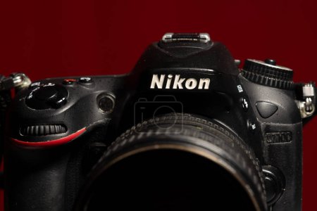Photo for Salvador, Bahia, Brazil - July 30, 2023: Close-up portrait of a professional DSLR camera by Nikon D7100, with Nikkor 16-85mm f 3.5 lens isolated on a red background. - Royalty Free Image