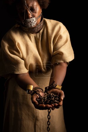 Téléchargez les photos : Portrait d'une femme noire enchaînée et portant un masque de fer sur son visage tenant des chaînes. Esclave Anastacia. Esclavage au Brésil. - en image libre de droit