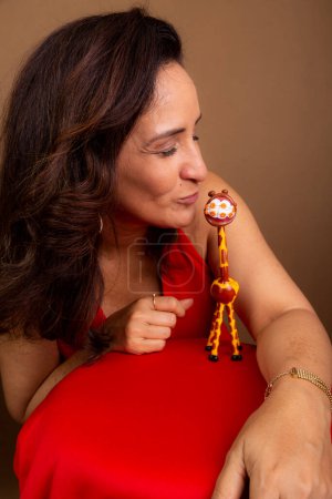Photo for Cheerful coaching woman kissing a giraffe doll. Symbol of non-violent communication. Isolated on brown background. - Royalty Free Image