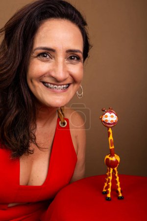 Photo for Coaching woman, happy, next to a giraffe doll. Symbol of non-violent communication. Isolated on brown background. - Royalty Free Image