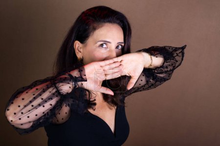 Photo for Coaching woman making hand gestures near her mouth. Surprise and stress sign. Motivational management. Isolated on brown background. - Royalty Free Image