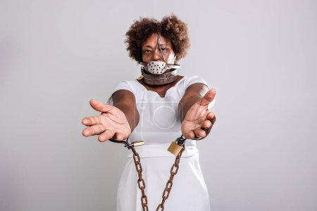 Photo for Portrait of sad woman bound with old rusty chains and padlocks, showing hands. Slave trade prevention concept. - Royalty Free Image
