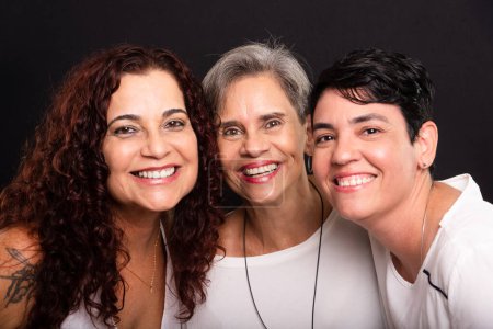 Téléchargez les photos : Photo studio de trois femmes, lesbiennes, heureuses et libres en regardant la caméra. Isolé sur fond noir. - en image libre de droit