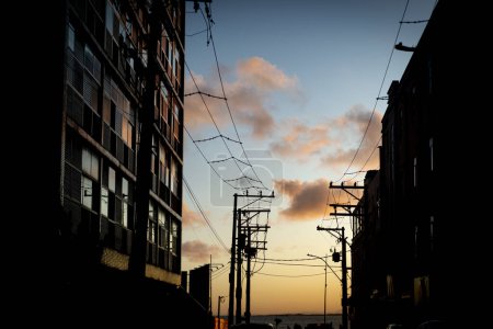 Téléchargez les photos : Silhouette de bâtiments résidentiels et fils de transport d'électricité contre le spectaculaire ciel de fin d'après-midi. Salvador, Brésil. - en image libre de droit
