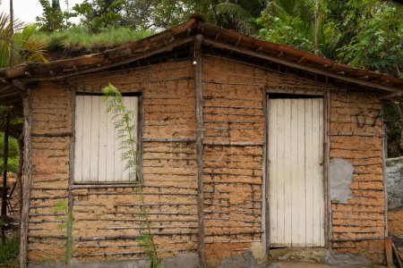 Téléchargez les photos : Aratuipe, Bahia, Brésil - 21 juin 2022 : Une maison en argile et des morceaux de bois. Situation d'extrême pauvreté. Ville d'Aratuipe, Bahia. - en image libre de droit