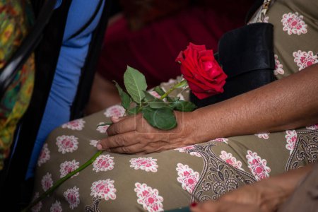 Eine Frau hält eine rote Rose in der Hand. Konzept der Religiosität.