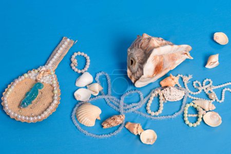 Several sea shells, necklaces and mirror scattered on the blue studio floor. Tribute to iemanja.