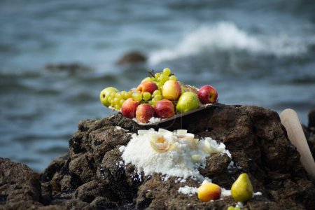 Vase de nourriture avec des fruits sur un rocher de plage. Hommage religieux. Salvador, Bahia.