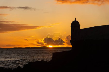 Beautiful dramatic orange sunset. Silhouette of the tip of a nautical fort.