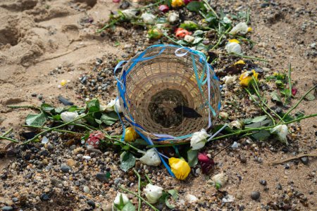 A basket surrounded by several colorful flowers on the sand of a beach. Religious tribute. Salvador, Bahia.