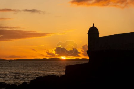 Beautiful dramatic orange sunset. Silhouette of the tip of a nautical fort.