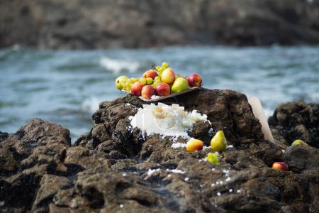 Food vase with fruits on top of a beach rock. Religious tribute. Salvador, Bahia.