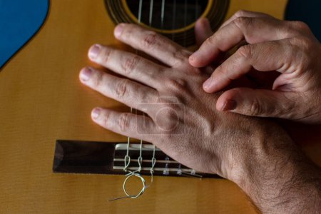 Hands of a classical guitarist on top of the guitar. 