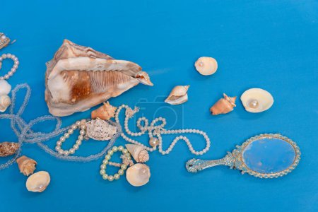 Varias conchas marinas, collares y espejos dispersos en el suelo del estudio azul. Homenaje a iemanja.