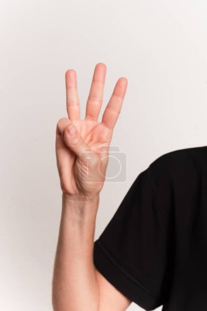 Primer plano de una mano haciendo la letra W en el lenguaje de señas para sordos en Brasil, Libras. Aislado sobre fondo blanco.