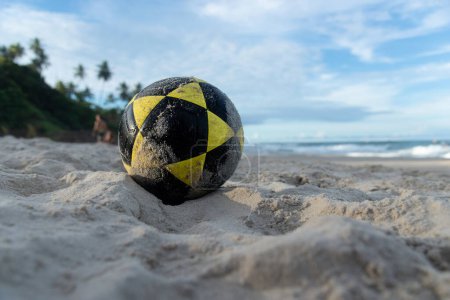 A sand soccer ball in the dunes against sea and blue sky. Leisure and sport.