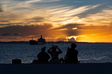 Foto de Salvador, Bahia, Brasil - 13 de abril de 2019: Los turistas, en silueta, se ven en Ponta de Humaita disfrutando de la puesta de sol en la ciudad de Salvador, Bahia. - Imagen libre de derechos