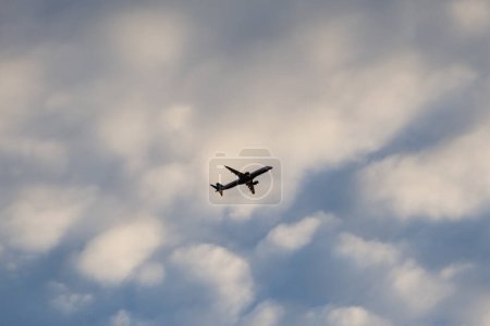 Téléchargez les photos : Un grand avion est vu dans le ciel avec plusieurs nuages blancs. Transports aériens. - en image libre de droit