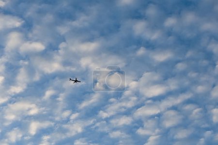 Téléchargez les photos : Un grand avion est vu dans le ciel avec plusieurs nuages blancs. Transports aériens. - en image libre de droit
