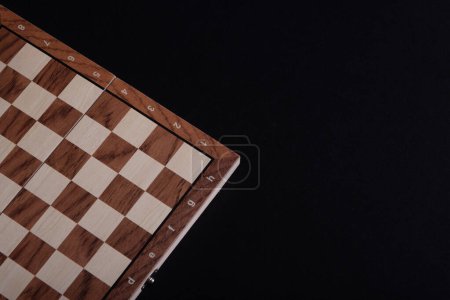 Foto de Parte de un tablero de ajedrez o damas de madera vacías sobre un fondo negro. - Imagen libre de derechos