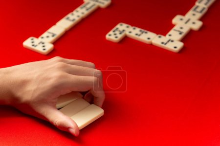 Domino player holding rectangular acrylic pieces. Board game. Red background.