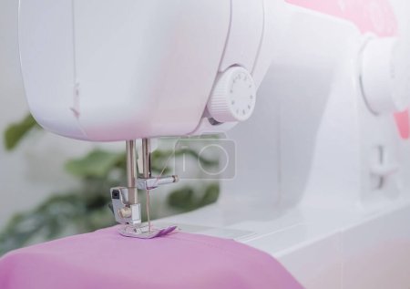 Téléchargez les photos : Gros plan de la machine à coudre travaillant avec du tissu violet, coudre de nouveaux vêtements. - en image libre de droit