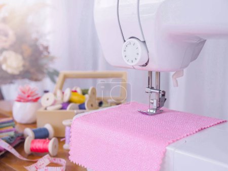 Téléchargez les photos : Gros plan de la machine à coudre travaillant avec du tissu rose, coudre de nouveaux vêtements. - en image libre de droit
