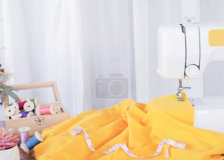 Téléchargez les photos : Gros plan de la machine à coudre travaillant avec du tissu jaune, coudre de nouveaux vêtements. - en image libre de droit