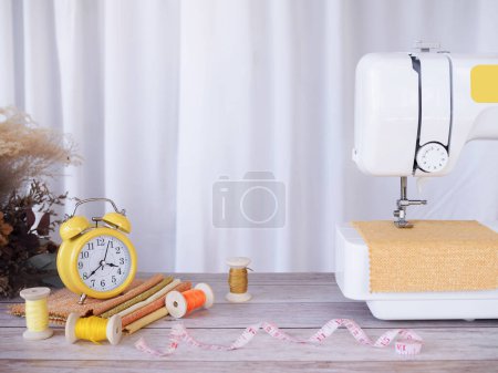Téléchargez les photos : Machine à coudre avec tissu jaune, accessoires de couture sur la table, couture de vêtements neufs. - en image libre de droit
