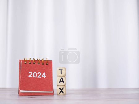 2024 desk calendar and Wooden blocks with the word TAX. The concept about prepare to pay tax in new year 2024