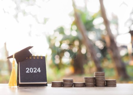 Study goals, 2024 Desk calendar with graduation hat and stack of coins. The concept of saving money for education, student loan, scholarship, tuition fees and manage time to success graduate.