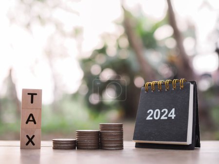 2024 desk calendar, Wooden block with word TAX and stack of coins. The concept of saving money for payment tax, Financial, Investment and Business growing in year 2024.