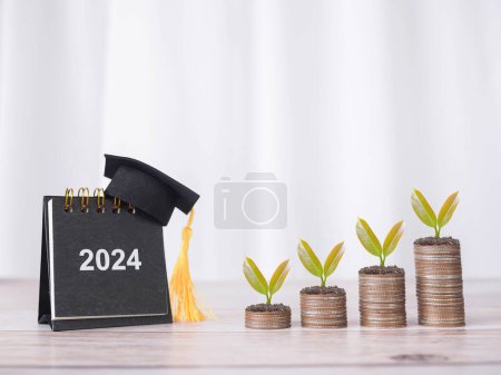 2024 desk calendar with graduation hat and plants growing up on stack of coins. The concept of saving money for education, student loan, scholarship, tuition fees in the future