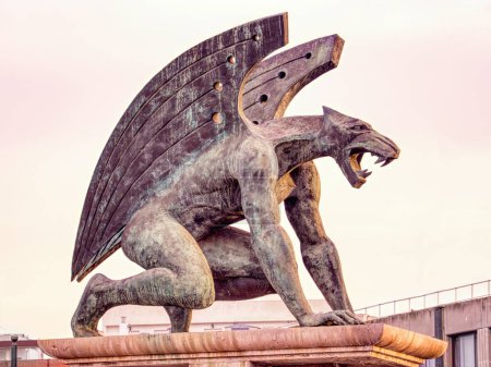 Téléchargez les photos : Statue en bronze de l'un des quatre Gargoyles gardiens du pont du royaume (pont del regne) à Valence, illuminée par le soleil couchant - en image libre de droit