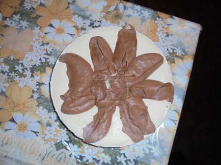 Téléchargez les photos : Une étrange nourriture vue du haut : un gâteau blanc avec une décoration de pâte brune ressemblant à un tas d'excréments, couché sur une table - en image libre de droit