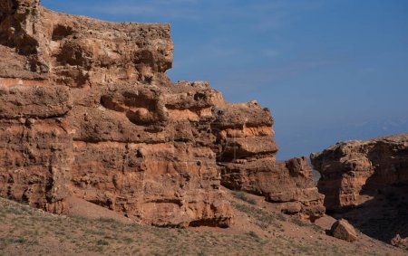 Große Felsformation vor tiefblauem Himmel. Die Oberfläche des Gesteins ist zerklüftet und steinig, mit Brauntönen, die auf Erosion durch Umweltelemente hindeuten.