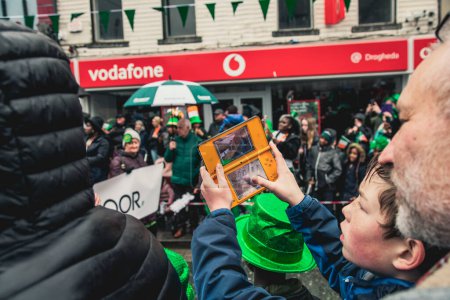 Photo for A boy filming the Saint Patrick's Day parade on a Nintendo 3DS - Royalty Free Image