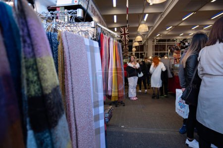 Foto de London - 02 27 2022: Market in Covent Garden with women strolling through the stalls of cloth and scarves - Imagen libre de derechos