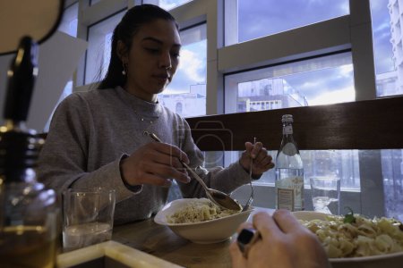 Téléchargez les photos : London - 03 06 2022: Close up of a girl with Latin or South American features eating a plate of fettuccine with cream - en image libre de droit
