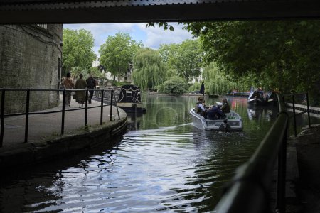 Photo for London - 05 29 2022: Boat with people sitting sailing under Harrow RD Bridge and entering Little Venice Basin. - Royalty Free Image