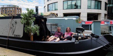 Photo for London - 06 03 2022: Couple rests on their houseboat on Regent's Canal near Battlebridge Basin - Royalty Free Image