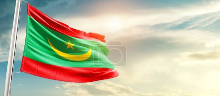 Mauritania waving flag in beautiful sky with sun